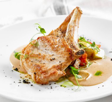 Biftek, sebze, garnitür ve sos. Kemikli domuz pirzolası. Köy tarzında ana yemek.