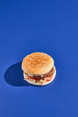 Sert gölgeli sığır burger mavisi arka plan. Amerikan abur cuburu çok az. Hamburger modasına uygun. Basit burger rengi arkaplan