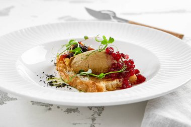 Kızarmış üzümlü kızarmış ekmek ve mikro yeşil tavuk ciğeri ezmesi. Beyaz tabakta tavuklu börek. Lezzetli aperatif, tost üzerine kaz ciğeri. Köy tarzında reçelli ciğer ezmesi.