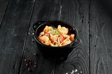 Kızarmış udon eriştesini tavada karidesle karıştır. Ahşap arka planda karidesli Udon eriştesi. Deniz ürünleri udonu. İçinde malzemeler olan Asya erişteleri. Japon restoranı için Wok menüsü