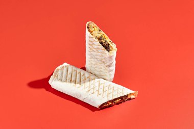 Shawarma dürümü, arka planda sert gölgeli sığır eti. Soyut tarzda etli shawarma sandviçi. Asgari konseptte basit bir fast food. Lübnan yemeği. Gölge güneş ışığı.