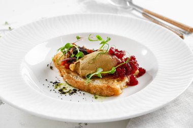 Kızarmış üzümlü kızarmış ekmek ve mikro yeşil tavuk ciğeri ezmesi. Beyaz tabakta tavuklu börek. Lezzetli aperatif, tost üzerine kaz ciğeri. Köy tarzında reçelli ciğer ezmesi.