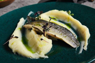 Patates püresi ile balık filetosu, gri arka planda deniz kabuğu filetosu ve patates kreması. Gri taş masadaki balık tabağı. Restoran için çağdaş balık menüsü. Estetik bileşim