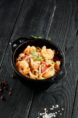 Kızarmış udon eriştesini tavada karidesle karıştır. Ahşap arka planda karidesli Udon eriştesi. Deniz ürünleri udonu. İçinde malzemeler olan Asya erişteleri. Japon restoranı için Wok menüsü