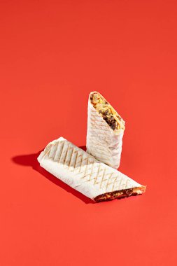 Shawarma dürümü, arka planda sert gölgeli sığır eti. Soyut tarzda etli shawarma sandviçi. Asgari konseptte basit bir fast food. Lübnan yemeği. Gölge güneş ışığı.