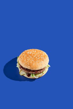 Sert gölgeli sığır burger mavisi arka plan. Amerikan abur cuburu çok az. Hamburger modasına uygun. Basit burger rengi arkaplan