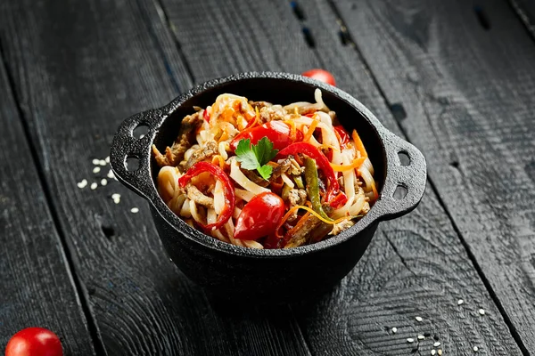 日本人はうどんをよく炒めます 木の背景に牛や野菜を入れたうどん 具材と黒テーブルの上にアジア麺 中華料理 — ストック写真