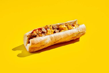 Asgari tarzda peynirli biftek. Sarı arka planda gölgeli Amerikan fast food 'u. Philadelphia biftekli sandviç moda konsepti. Renk arkaplanındaki abur cubur
