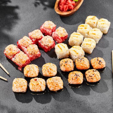 Ateşli maki, kara tahta üzerine kurulmuş. Çeşitli ekmeklerle hazırlanmış fırında suşi. Somon, tobiko, yengeç ve fırında peynirli suşi. Siyah arka planı, yaprakları ve sert gölgesi olan tarz konsept suşi menüsü