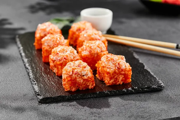 Kara tahtada fırında Maki suşisi. Yengeçli sıcak California maki. Masugo 'lu suşi rulosu, fırında peynir ve yengeç. Siyah arka planı, yaprakları ve sert gölgesi olan Japon tarzı bir menü.