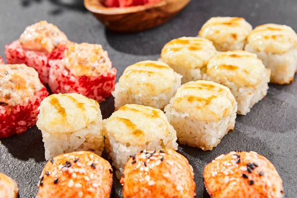 Ateşli maki, kara tahta üzerine kurulmuş. Çeşitli ekmeklerle hazırlanmış fırında suşi. Somon, tobiko, yengeç ve fırında peynirli suşi. Siyah arka planı, yaprakları ve sert gölgesi olan tarz konsept suşi menüsü