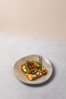 Gri seramik tabakta ahtapot, sebze ve sos. Ahtapotlu tost, çağdaş tarzda. Modern seramik bulaşık takımında şef konsepti bruschetta. El yapımı yemek tabağı.