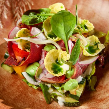 Pastırmalı salata, sebze ve el yapımı seramik kasede sos. Gri taşlı arka planda modern bulaşık takımında biftek ve sebze salatası. Şef 'ten çağdaş yemek. El yapımı yemek tabağı.