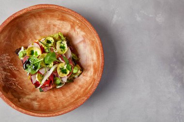 Pastırmalı salata, sebze ve el yapımı seramik kasede sos. Gri taşlı arka planda modern bulaşık takımında biftek ve sebze salatası. Şef 'ten çağdaş yemek. El yapımı yemek tabağı.