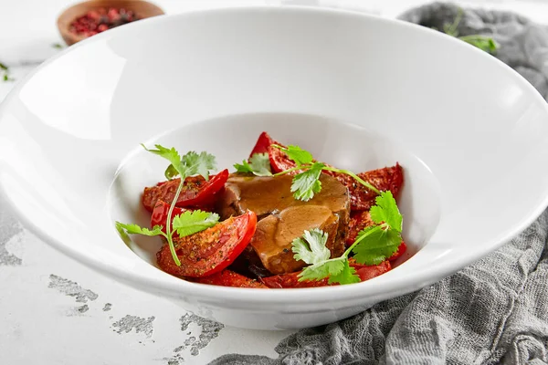 Sos ve kurutulmuş domatesli kızarmış sığır dili. Biftek dilinden et yemeği ve sebze garnitürü. Lezzetli ana yemek - öküz dili