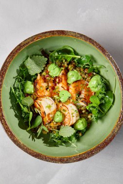 Yeşil kase, karides, kinoa ve el yapımı seramik tabakta avokado kreması. Karanlık modern bulaşık takımında karidesli salata. Modern tarzda sağlıklı yiyecekler..