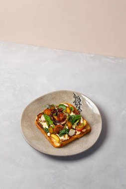 Gri seramik tabakta ahtapot, sebze ve sos. Ahtapotlu tost, çağdaş tarzda. Modern seramik bulaşık takımında şef konsepti bruschetta. El yapımı yemek tabağı.