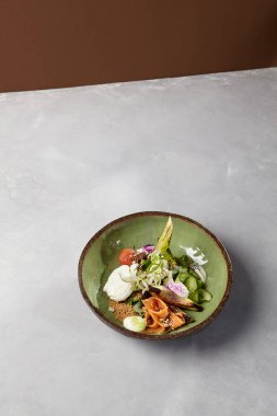 Somon, avokado, brokoli, sebze ve yumurta ile ev yapımı seramik tabakta salata kasesi. Modern servis takımında somon, brokoli ve kinoa ile Buda kasesi. Beton zeminde modern seramik bulaşık takımı
