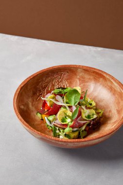 Pastırmalı salata, sebze ve el yapımı seramik kasede sos. Gri taşlı arka planda modern bulaşık takımında biftek ve sebze salatası. Şef 'ten çağdaş yemek. El yapımı yemek tabağı.