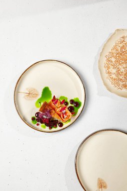 Yenilikçi tarifler. El yapımı seramik tabakta maydanoz yağlı somon peynirli kek. Çağdaş bulaşık takımında somonlu cheesecake beyaz beton masada. Sert gölgeli modern yemekler.