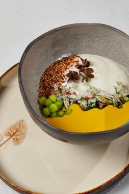 El yapımı seramik kasede yengeçli balkabağı çorbası. Yenilikçi tarifler. Beyaz beton arka planda yengeç ve peynir espumalı krema çorbası. Bulaşık takımında modern yemek