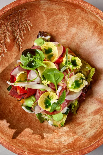 Pastırmalı salata, sebze ve el yapımı seramik kasede sos. Gri taşlı arka planda modern bulaşık takımında biftek ve sebze salatası. Şef 'ten çağdaş yemek. El yapımı yemek tabağı.