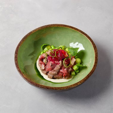 Aperatif, soslu biftek, salatalık ve seramik kasede soğan. Modern seramik bulaşık takımında biftek. El yapımı yemek tabağı. Modern yemek, el yapımı bulaşık takımı.