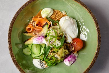 Somon, avokado, brokoli, sebze ve yumurta ile ev yapımı seramik tabakta salata kasesi. Modern servis takımında somon, brokoli ve kinoa ile Buda kasesi. Beton zeminde modern seramik bulaşık takımı