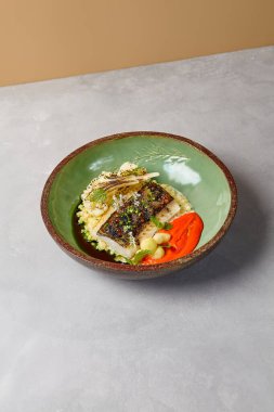 Bulgur, ızgara karnabahar ve domates soslu but fileto. Pişmiş balık filetosu ve el yapımı seramik bulaşık takımı. Minimalist tarzda modern yemekler.