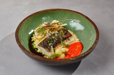 Bulgur, ızgara karnabahar ve domates soslu but fileto. Pişmiş balık filetosu ve el yapımı seramik bulaşık takımı. Minimalist tarzda modern yemekler.