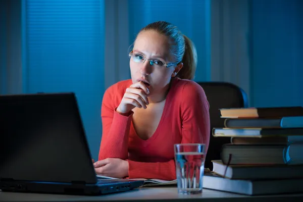 Jonge vervelen vrouwelijke college student studeert slecht op laat in de avond Stockfoto