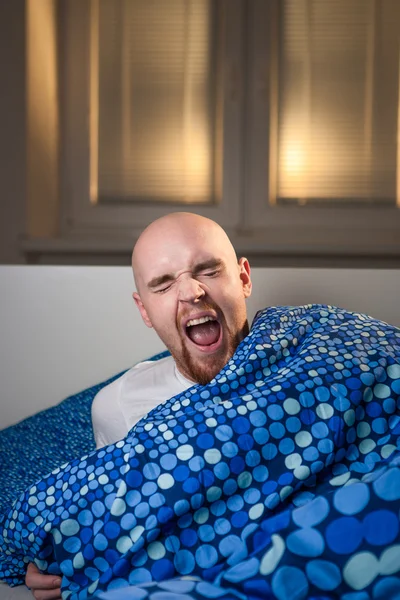 Hombre joven en la cama con dolor de cabeza depresión y bostezo resaca — Foto de Stock