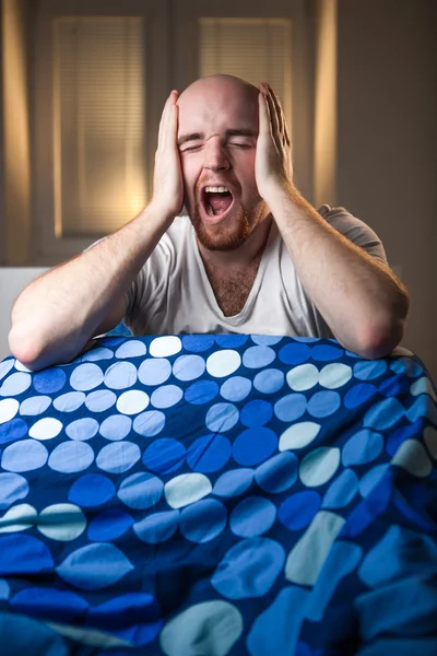 Hombre joven en la cama con dolor de cabeza depresión y bostezo resaca — Foto de Stock