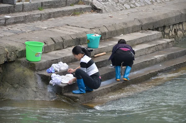 Chinese women washes cloth on the river bank