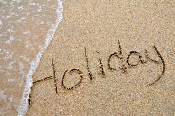 Holiday word written on sandy beach — Stock Photo, Image