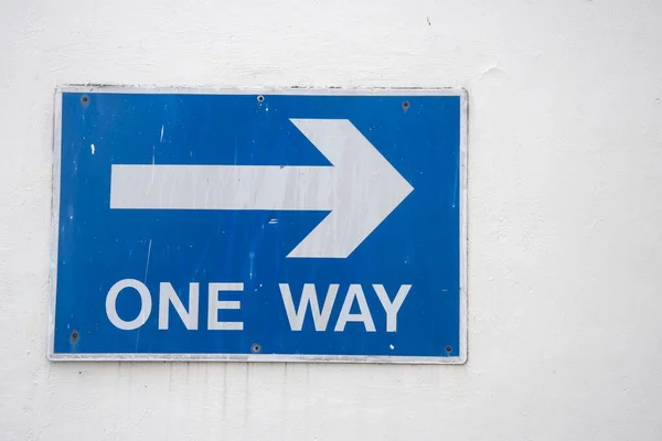 One way right arrow sign on the wall. White on blue background