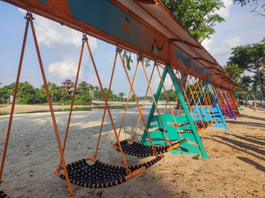 Singapur - 2 Nisan 2022 Sentosa, Singapur 'da Sentosa Hamak Swing. İkonik köprünün yakınındaki Palawan Sahili 'nde bulunan ultra uzun hamak salıncağı 18 kişiye sığabiliyor..