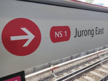 Singapur - 3 Nisan 2022: Kırmızı ok MRT platformundaki Jurong Doğu istatistiklerinin yönünü gösteriyor. Mass Rapid Transit veya MRT, Singapur 'da ana ulaşım modudur.