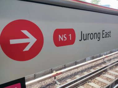 Singapur - 3 Nisan 2022: Kırmızı ok MRT platformundaki Jurong Doğu istatistiklerinin yönünü gösteriyor. Mass Rapid Transit veya MRT, Singapur 'da ana ulaşım modudur.