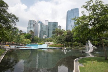 Kuala Lumpur, Malezya - Haziran 2022: Güneşli bir günde KLCC parkında balina ve yunus heykelleri içeren bir şelale çeşmesinin güzel manzarası.