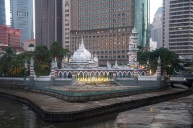 Kuala Lumpur, Malezya - Haziran 2022: Kuala Lumpur 'daki mali ve bankacılık gökdelenlerinin arka planında bir Cami Mescid Jamek olan modern şehir manzarası