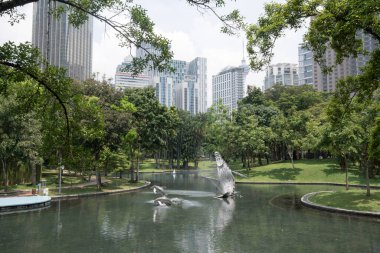Kuala Lumpur, Malezya - Haziran 2022: Güneşli bir günde KLCC parkında balina ve yunus heykelleri içeren bir şelale çeşmesinin güzel manzarası.