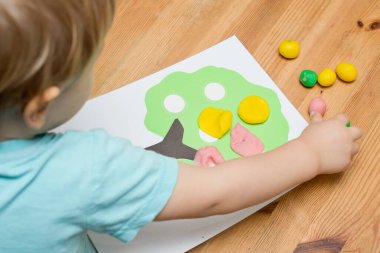 Çocuk bir mankenle oynuyor. Elma boyası ve ahşap üzerine yapıştırıcı. Montessori malzemeleri. Gelişme, eğitim. Anaokulu çocukları için eğitici oyuncaklar. Evde etkinlik.