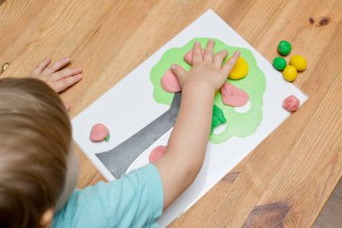 Çocuk bir mankenle oynuyor. Elma boyası ve ahşap üzerine yapıştırıcı. Montessori malzemeleri. Gelişme, eğitim. Anaokulu çocukları için eğitici oyuncaklar. Evde etkinlik.