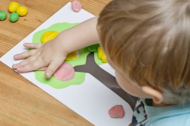 Çocuk bir mankenle oynuyor. Elma boyası ve ahşap üzerine yapıştırıcı. Montessori malzemeleri. Gelişme, eğitim. Anaokulu çocukları için eğitici oyuncaklar. Evde etkinlik.