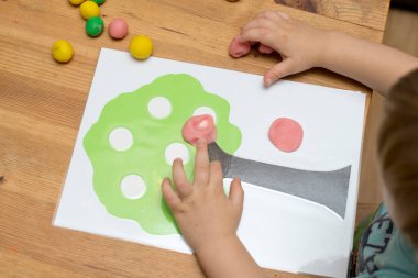 Çocuk bir mankenle oynuyor. Elma boyası ve ahşap üzerine yapıştırıcı. Montessori malzemeleri. Gelişme, eğitim. Anaokulu çocukları için eğitici oyuncaklar. Evde etkinlik.