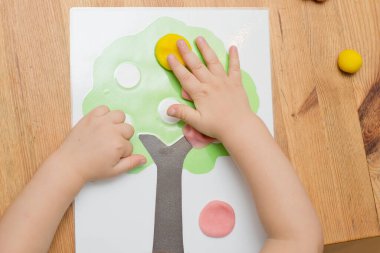 Çocuk bir mankenle oynuyor. Elma boyası ve ahşap üzerine yapıştırıcı. Montessori malzemeleri. Gelişme, eğitim. Anaokulu çocukları için eğitici oyuncaklar. Evde etkinlik.