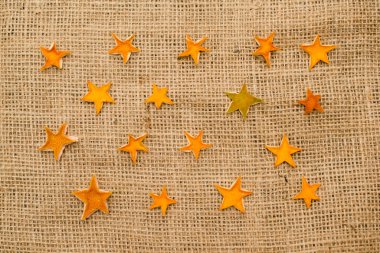 Kurutulmuş portakal kabuğundan yapılmış yıldızlar keten kumaş üzerinde. Noel süsü. Advent süslemeleri.