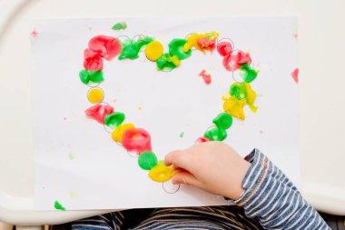 Annem için sevgililer günü tebrik kartı hazırlıyorum. Küçük çocuk baskılı kağıt kalbe hamur uyguluyor. Güzel motor beceriler, parmak koordinasyonu. bebekler için erken eğitim