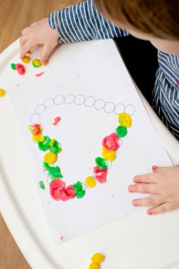 Annem için sevgililer günü tebrik kartı hazırlıyorum. Küçük çocuk baskılı kağıt kalbe hamur uyguluyor. Güzel motor beceriler, parmak koordinasyonu. bebekler için erken eğitim